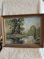 Full view of the framed painting resting on a white textured background, displaying the lake, swans, trees, and gazebo scene.