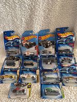 Top view of 14 Hot Wheels cars in original packaging, showing mix of cars and packaging condition