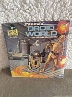 Front of sealed 'Star Wars: Droid World - The Further Adventures' package showing droid artwork and indication of 24 page book and record included.