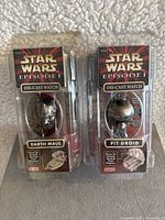 Front view of two Star Wars Episode I die-cast watches in original sealed packaging, featuring Darth Maul and Pit Droid designs.