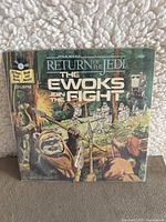 Front cover of the book and record set titled 'Return of the Jedi: The Ewoks Join the Fight' showing Ewoks and Star Wars characters in forest battle scene.