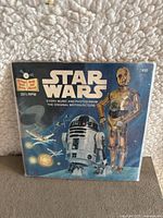 Front cover of the vinyl record sleeve featuring Star Wars characters R2-D2, C-3PO, and other elements from the original movie.