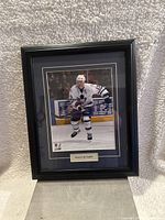 Black wood frame with glass, featuring Mats Sundin in action on ice in a white Toronto Maple Leafs jersey with captain's C, blue and gold matting, and nameplate.