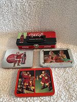 Front view of 4 Coca-Cola collectible tins with Christmas holiday themed artwork including Santa Claus and children