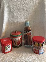 Front view of the four Coca-Cola metal tins showing sizes and vintage graphics