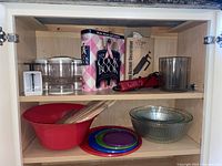 Shelf with electric bag sealer box, vintage cookbook, food scale, three flip jars, red plastic bowl with skewers, Pampered Chef Accent Decorator, and clear glass Pyrex bowls.
