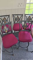 Five black metal swivel bar stools with magenta slipcovers on seats, showing the overall lot condition.