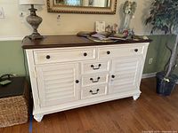 Front view of the white buffet table with dark wood top, showing drawers and cabinet doors.