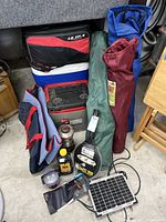 Overview of camping gear including chairs, coolers, lantern, bug zapper, carrying bags and solar panel.
