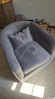 Front view of gray velvet swivel chair with a matching lumbar pillow on the seat cushion. Shows the stain on the seat cushion.