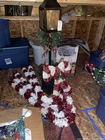 Lamppost and candy cane decorations boxed and standing on wooden floor among bins and boxes in attic.