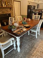 Wood rectangular dining room table with brown leaf and white spindle-turned legs, some decorative items placed on tabletop.