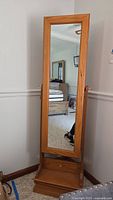 Full front view of the oak wood standing dressing mirror with mirror surface reflecting a room.