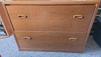 Front view of wooden 2-drawer lateral file cabinet showing exterior condition and wooden handles.