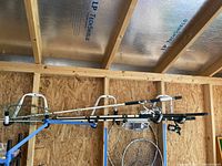 Five fishing rods and three fishing nets mounted on a wooden structure.