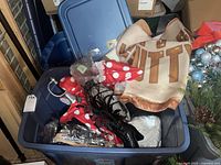 Open storage tub containing multiple costume items including a polka dot dress and a themed cape/blanket with the word 'NUTT'