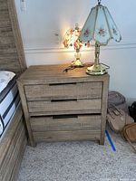 Wooden nightstand in rustic light brown with four drawers and recessed horizontal handles, photographed from front view showing texture and construction details.