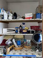 Shelves with assorted lightbulbs, hair straightener, personal care items, baskets with nail care tools, mirror, towels