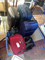 Photo showing three rolling suitcases in black, blue, and purple colors stacked together.