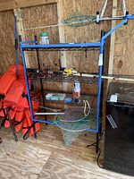 Front and side views of metal wire shelf with blue protective tape on edges, with fishing equipment present but not included.