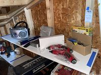 Wide view of shelf with Emerson boombox, ViewSonic box, PanDigital wand, boxed screwdrivers, lantern, and Pictionary game.