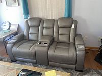 Front view of gray reclining loveseat showing two seats and center console with cup holders