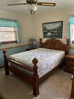 Full view of the solid wood bed frame with mattress in a bedroom setting showing overall condition and style.