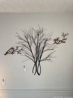 Full view of the metal wall art showing large tree sculpture with two bird sculptures mounted separately on the wall.