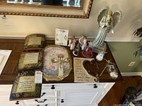 Overview photo of spiritual wall art items on a wooden dresser including plaques, crosses, and figurines