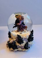 Front view of the glass snow globe showing two Boyds Bears embracing inside a snowy pine tree base.