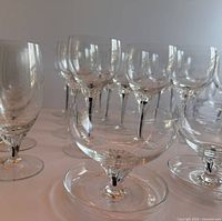 Clear crystal stemmed glasses with black stems arranged on a table, showing wine glass shape in focus and multiple glasses behind