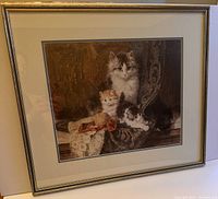 Framed picture of a mother cat with three kittens on a fabric with lace and ribbon.