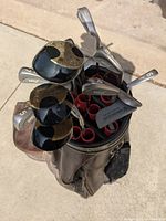 Top view of golf clubs showing numbered irons and woods with black and gold MCX heads inside the bag.