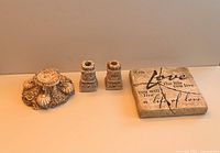 Front view of the three decorative candle holders and the square plaque with an inspirational inscription