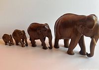 Four teak elephant figurines of varying sizes lined up in a row