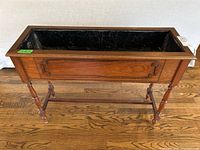 Front view of rectangular wooden planter showing decorative side panel and metal liner