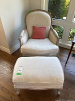 Front view of Bergere armchair with ottoman in front on hardwood floor