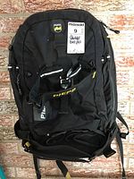 Full view of the black Pieps backpack showing front compartments and buckles.