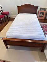 View from foot of the bed showing wooden footboard and mattress on top.