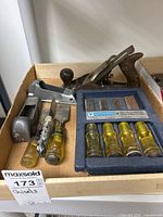 Box containing 2 Stanley wood planes and a 4-piece Mastercraft wood chisel set with yellow translucent handles all arranged neatly.