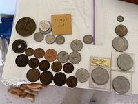 Assortment of coins displayed on a white surface including Canadian, British, and US coins, some in protective holders.