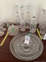 Wide view showing the three labeled crystal decanters, smaller decanter, covered butter dish, chip and dip bowl, cruet, and platter.