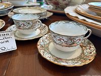 Two Doulton Burslem teacups on matching saucers showing detailed floral and gold trim patterns