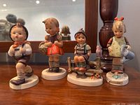 Front view of four Goebel Hummel figurines showing details and colors