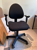 Front view of black Ikea desk chair with fabric upholstery, armrests, and caster base.