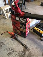 Toro Ultra Electric Blower Vac with original box and Black & Decker hedge trimmer on garage floor.