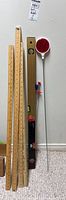 Photo showing three foldable wooden rulers, wooden torpedo level, smaller black torpedo level, and two reflective driveway markers with red circular reflectors.