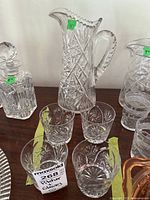 Four crystal glasses arranged in front of the pitcher displaying matching cut star and crosshatch patterns consistent with the pitcher.