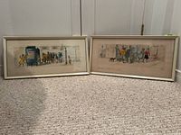 Both framed prints shown side by side on carpeted floor against door