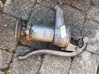 Metal well hand pump laid on stone pavement. Body has embossed text No 2 P882 16612 with visible rust and wear.